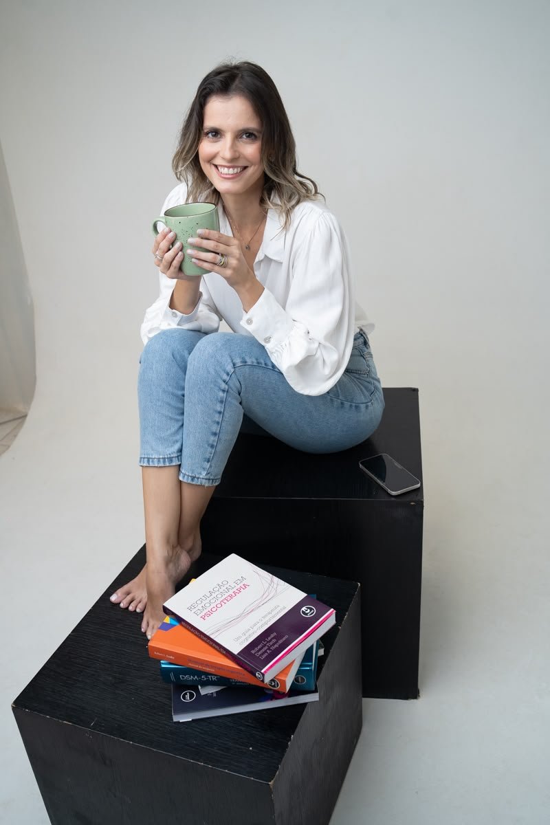 Polyana Labre com livros de psicologia em seu espaço de atendimento